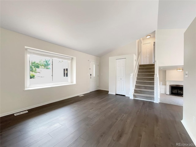 unfurnished living room featuring lofted ceiling and dark wood-type flooring