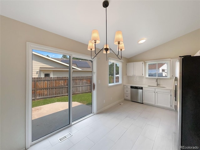 kitchen with pendant lighting, lofted ceiling, appliances with stainless steel finishes, white cabinetry, and decorative backsplash