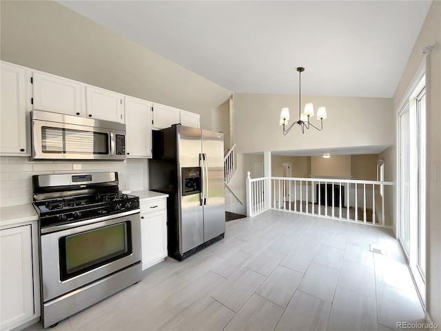 kitchen featuring decorative light fixtures, tasteful backsplash, white cabinetry, lofted ceiling, and stainless steel appliances