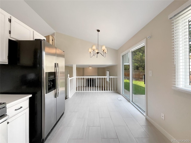 kitchen with a wealth of natural light, stainless steel fridge, pendant lighting, and white cabinets