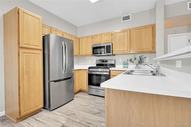 kitchen with light wood-type flooring, stainless steel appliances, sink, and light brown cabinets