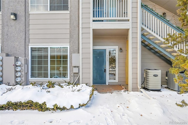 snow covered property entrance with cooling unit