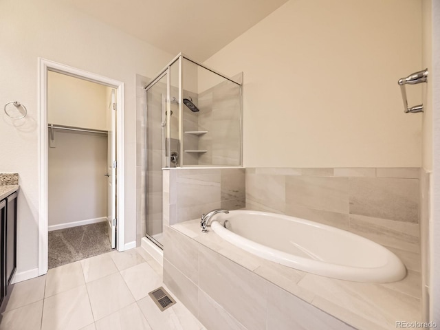 600 E Dry Creek Pl, Littleton, CO 80122 - bathroom featuring a stall shower, a bath, a walk in closet, vanity, and tile patterned floors
