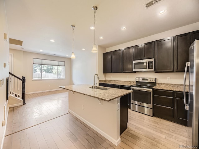 600 E Dry Creek Pl, Littleton, CO 80122 - kitchen with stainless steel appliances, light wood-style flooring, light stone counters, pendant lighting, and a kitchen bar