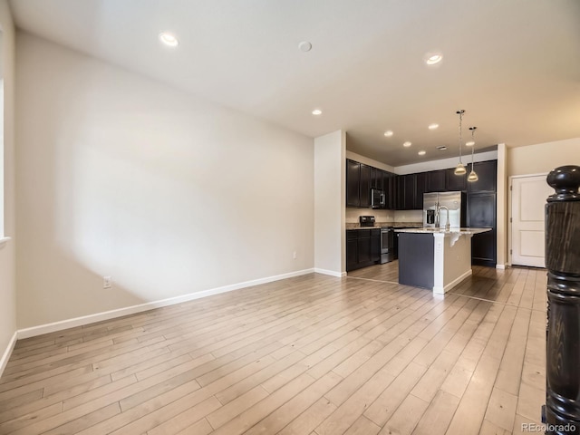 600 E Dry Creek Pl, Littleton, CO 80122 - kitchen with stainless steel appliances, open floor plan, a kitchen breakfast bar, a kitchen island with sink, and light wood-style floors