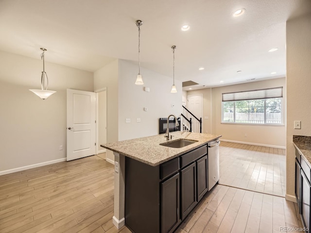 600 E Dry Creek Pl, Littleton, CO 80122 - kitchen with dishwasher, light wood-style flooring, a kitchen island with sink, light stone counters, and decorative light fixtures