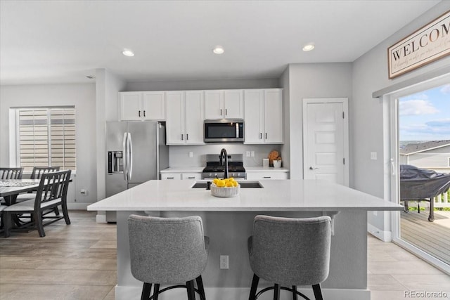 3344 Evening Pl, Castle Rock, CO 80109 - kitchen featuring appliances with stainless steel finishes, a sink, white cabinets, a breakfast bar, and light countertops