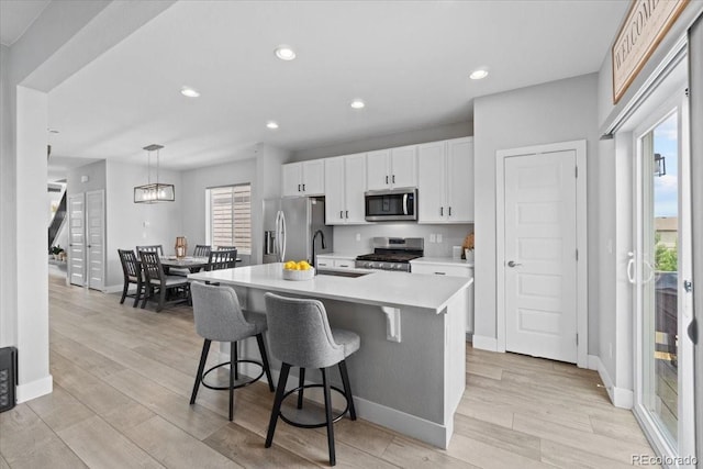 3344 Evening Pl, Castle Rock, CO 80109 - kitchen featuring appliances with stainless steel finishes, light countertops, an island with sink, light wood finished floors, and a sink
