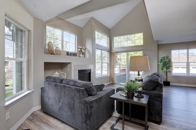 12812 Jasmine St Unit D, Thornton, CO 80602 - living area featuring plenty of natural light, a tile fireplace, high vaulted ceiling, and wood finished floors