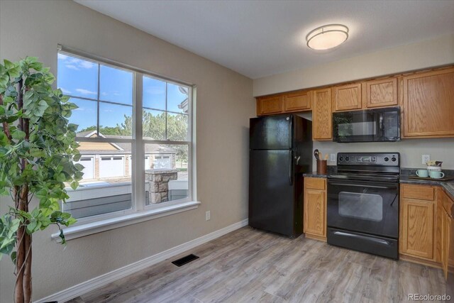 12812 Jasmine St Unit D, Thornton, CO 80602 - kitchen featuring black appliances, dark countertops, and light wood finished floors