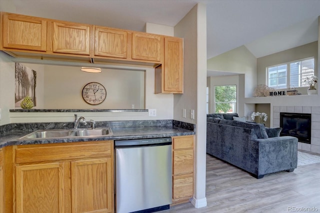 12812 Jasmine St Unit D, Thornton, CO 80602 - kitchen with dishwasher, light wood finished floors, lofted ceiling, dark countertops, and a tile fireplace