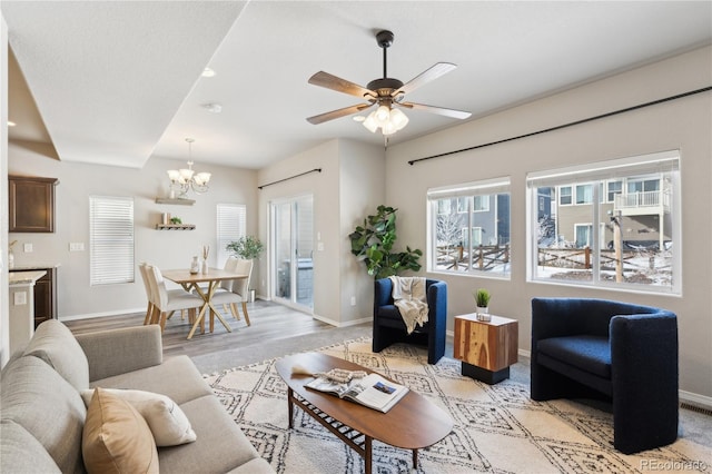 living room with ceiling fan with notable chandelier and light hardwood / wood-style floors