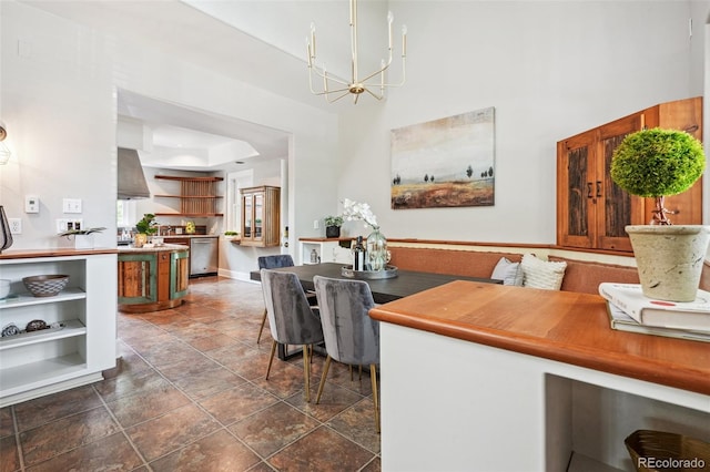 dining area with a notable chandelier, dark tile patterned flooring, and a tray ceiling