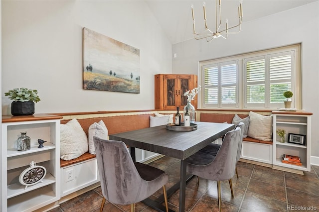 dining space with dark tile patterned floors, high vaulted ceiling, and an inviting chandelier