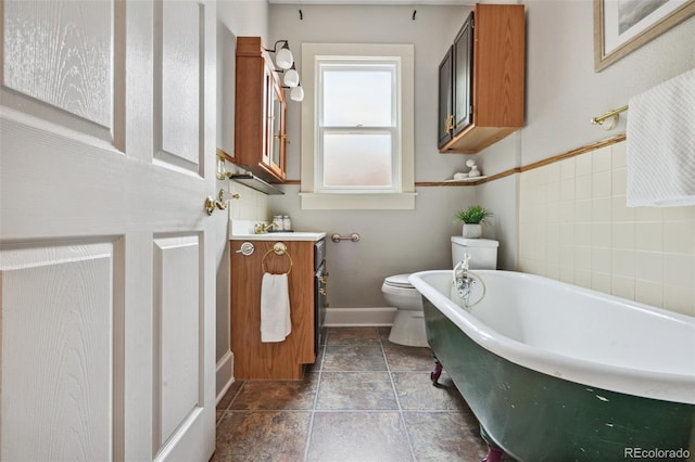 full bath featuring baseboards, a freestanding bath, vanity, and toilet