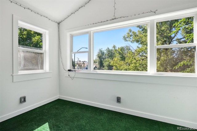 spare room featuring dark carpet and lofted ceiling