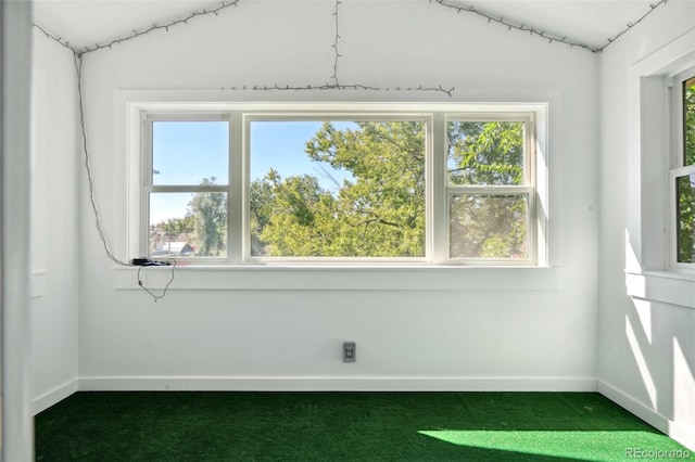 unfurnished room featuring baseboards and dark colored carpet