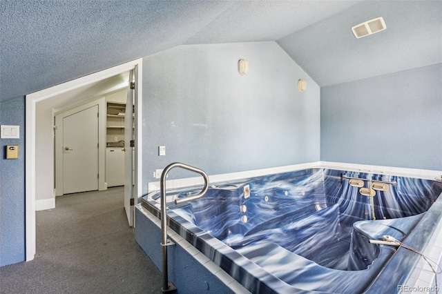 carpeted bedroom featuring a textured ceiling and vaulted ceiling