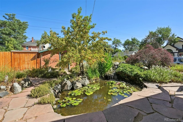 view of yard featuring a small pond and fence