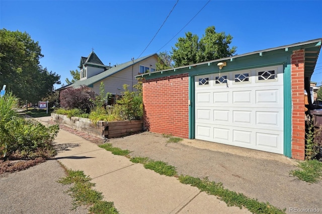 exterior space with driveway, brick siding, and an outdoor structure