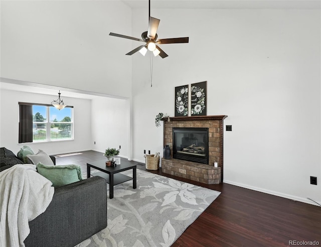 living room featuring wood finished floors, high vaulted ceiling, a fireplace, ceiling fan, and a chandelier