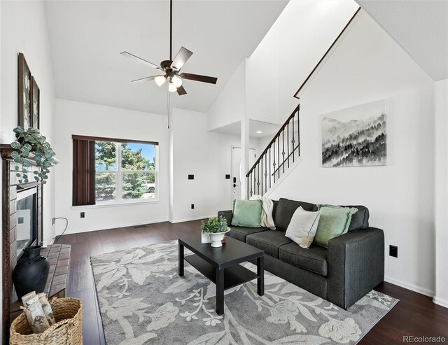 living room featuring wood-type flooring, a ceiling fan, high vaulted ceiling, and stairs