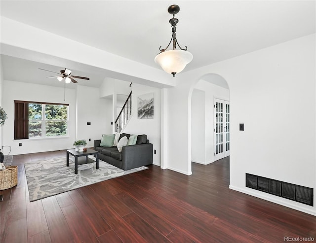 living room featuring a ceiling fan, stairs, arched walkways, and wood finished floors