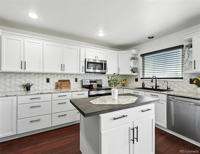 kitchen featuring appliances with stainless steel finishes, dark wood-style floors, white cabinetry, tasteful backsplash, and a kitchen island
