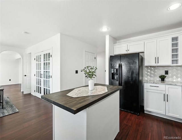 kitchen featuring black fridge with ice dispenser, arched walkways, dark wood-type flooring, open shelves, and recessed lighting