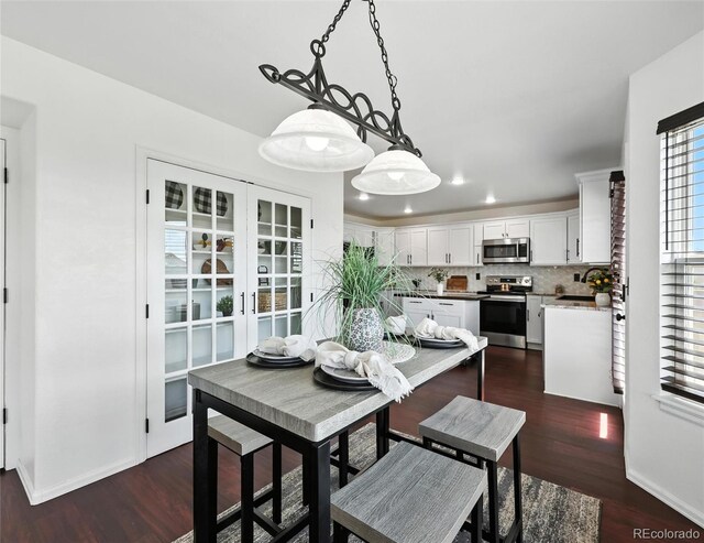 dining room with dark wood-type flooring, recessed lighting, and french doors