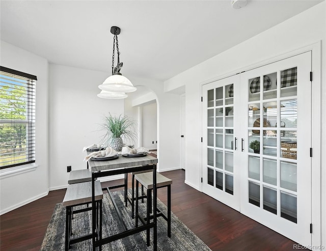 dining area with arched walkways, dark wood-style flooring, and french doors