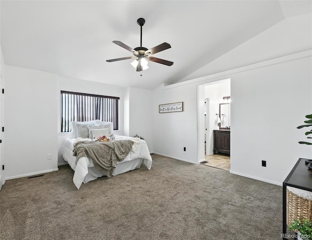 carpeted bedroom featuring vaulted ceiling, ensuite bath, and ceiling fan