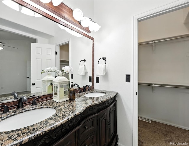 full bathroom featuring double vanity, a walk in closet, and ceiling fan