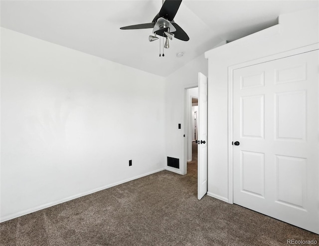 unfurnished bedroom with dark carpet, vaulted ceiling, and a ceiling fan