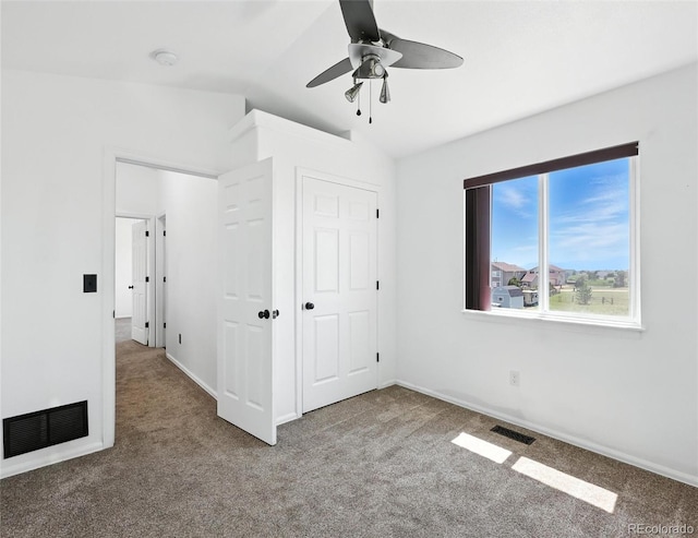 unfurnished bedroom with carpet, vaulted ceiling, a closet, and a ceiling fan