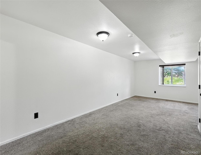 carpeted empty room with a smoke detector and a textured ceiling