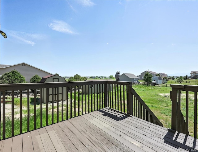 wooden deck featuring a storage shed, a residential view, and a lawn