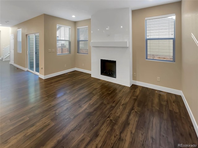 unfurnished living room featuring a large fireplace and dark hardwood / wood-style flooring