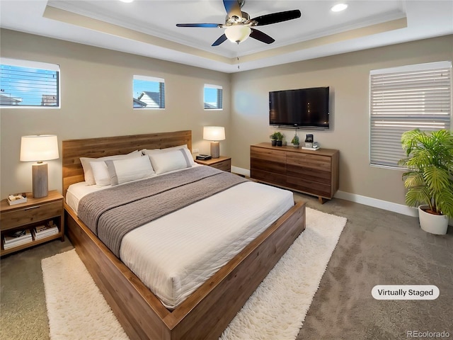 bedroom with ceiling fan, dark carpet, a raised ceiling, and ornamental molding