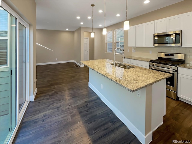 kitchen featuring sink, stainless steel appliances, an island with sink, pendant lighting, and white cabinets