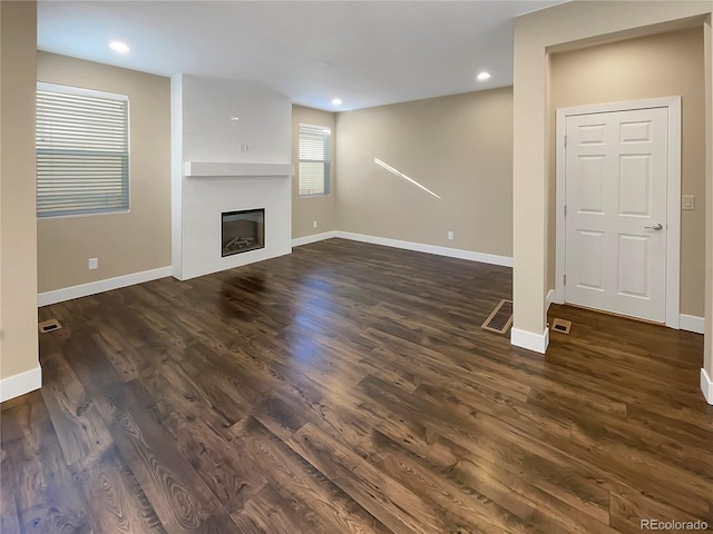 unfurnished living room featuring a fireplace and dark wood-type flooring