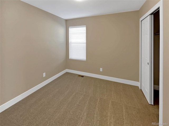 unfurnished bedroom with light colored carpet and a closet