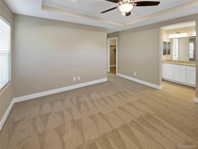 spare room featuring ceiling fan, light colored carpet, ornamental molding, and a tray ceiling