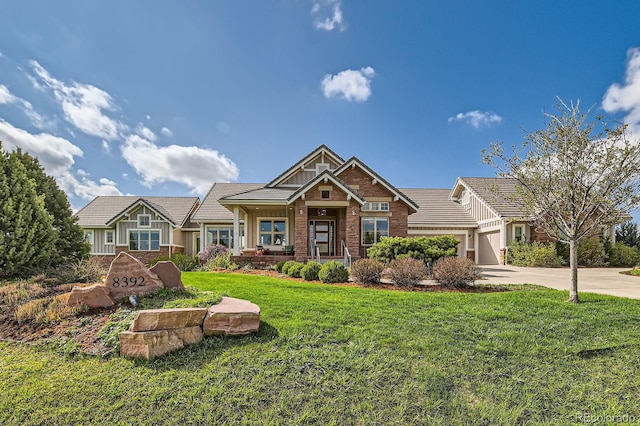 craftsman house with a tiled roof, a garage, brick siding, a front lawn, and concrete driveway