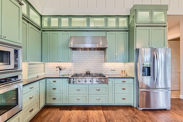 kitchen featuring ventilation hood, appliances with stainless steel finishes, backsplash, and green cabinets