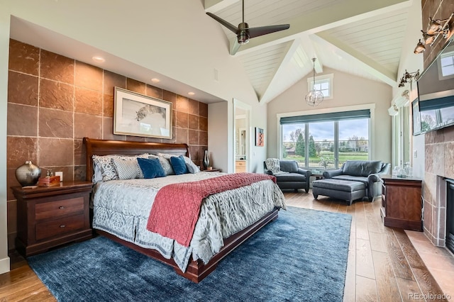 bedroom featuring wood-type flooring, tile walls, a tiled fireplace, and beam ceiling