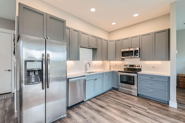 kitchen with light countertops, stainless steel appliances, a sink, and backsplash