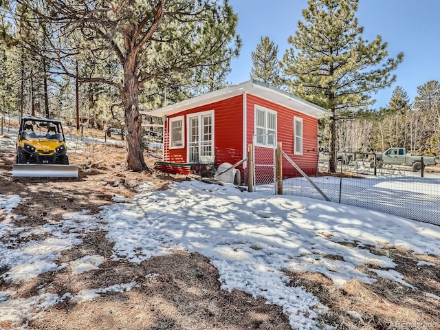 snow covered structure featuring an outbuilding