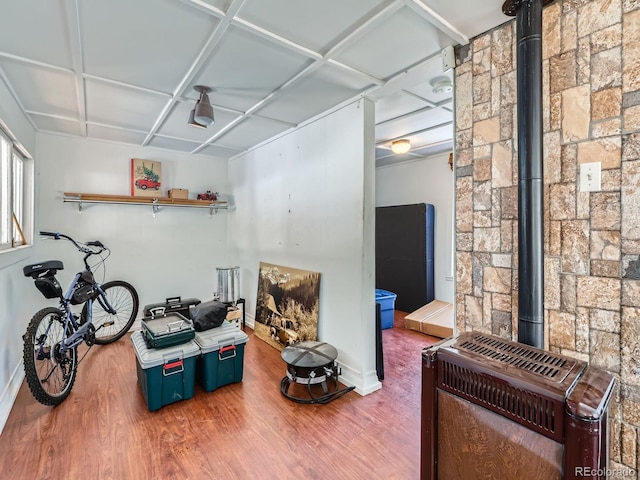 misc room with heating unit, wood finished floors, and a wood stove