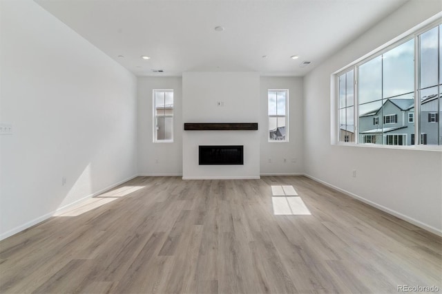 unfurnished living room featuring light hardwood / wood-style flooring and a healthy amount of sunlight